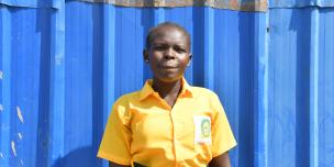 Ajus poses for the camera behind their classroom. Photo Credit: Yangi Teresa Justine/ Oxfam