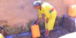 Ms. Feleg G/mariam, 65, fills a jerrycan at Meshano spring water point in Tigray, Ethiopia after the spring was rehabilitated.