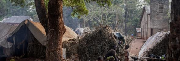 Yvonne and her two daughters prepare a meal next to their home on the Cesacoba site near Bangassou, Central African Republic, 2021. Adrienne Surprenant/ Oxfam
