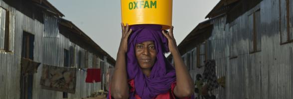 Zinab Alzaki Mohammed Alnur, 20, a Sudan refugee displaced by the war carrying a bucket of water at the transit centre in Renk. Oxfam is the lead WASH partner supporting thousands of refugees. Credit: Peter Caton/Oxfam
