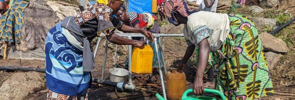 Puisage d'eau sur une rampe de distribution installée par Oxfam dans le site de Kasirusiru. Photo Credit: Yves Kalwira/ Oxfam