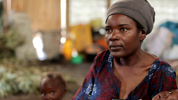 Feza Damani, mother of seven, fled the village of Kiwanja in the Rutshuru region. She has been living in Rusayo since September 2023. Mrs Feza and her seven children now live in a communal warehouse with several other displaced people. Photo credit: Yves Kalwira/ Oxfam Feza Damani, mother of seven, fled the village of Kiwanja in the Rutshuru region. She has been living in Rusayo since September 2023. Mrs Feza and her seven children now live in a communal warehouse with several other displaced people. Photo credit: Yves Kalwira/ Oxfam