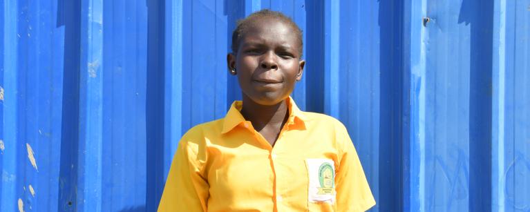 Ajus poses for the camera behind their classroom. Photo Credit: Yangi Teresa Justine/ Oxfam