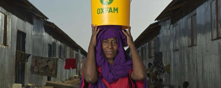 Zinab Alzaki Mohammed Alnur, 20, a Sudan refugee displaced by the war carrying a bucket of water at the transit centre in Renk. Oxfam is the lead WASH partner supporting thousands of refugees. Credit: Peter Caton/Oxfam