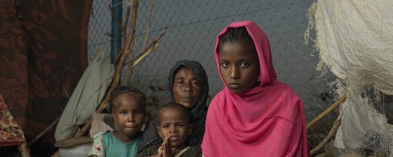 Asia*, a young refugee girl who fled the war in Sudan, sits outside her makeshift home in Renk. Credit: Peter Caton/Oxfam