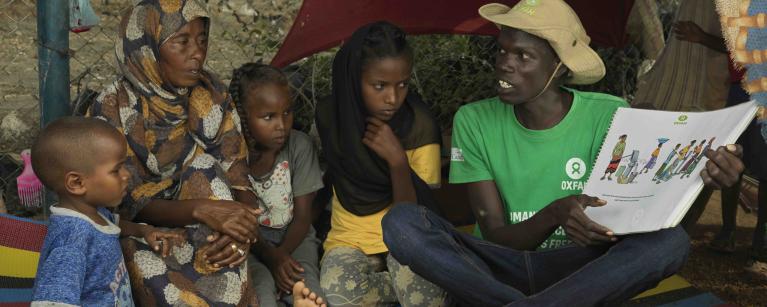 Photo 2.2 Saud Yosif Idris Mahmou, 40, with her daugther Asia* and her other children are taught by Jackman at Oxfam at their shelter about sanitation at the transit center in Renk.