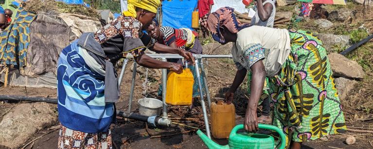 Puisage d'eau sur une rampe de distribution installée par Oxfam dans le site de Kasirusiru. Photo Credit: Yves Kalwira/ Oxfam