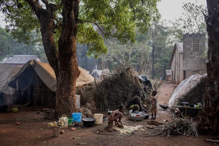 Yvonne and her two daughters prepare a meal next to their home on the Cesacoba site near Bangassou, Central African Republic, 2021. Adrienne Surprenant/ Oxfam