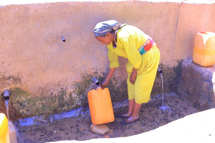Ms. Feleg G/mariam, 65, fills a jerrycan at Meshano spring water point in Tigray, Ethiopia after the spring was rehabilitated.