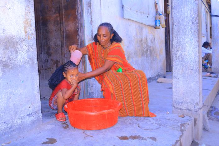Ms. Birey Yohans Werede washes her daughter’s hair outside their shelter in Asgede Woreda, Tigray.