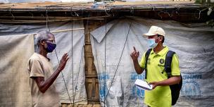 Oxfam volunteer Zahid Hossain, age 20, talking to Abdul Malek, age 80, about the precautions elderly people should take to prevent Covid-19. Cox’s Bazar refugee camp, Bangladesh. Photo: Fabeha Monir