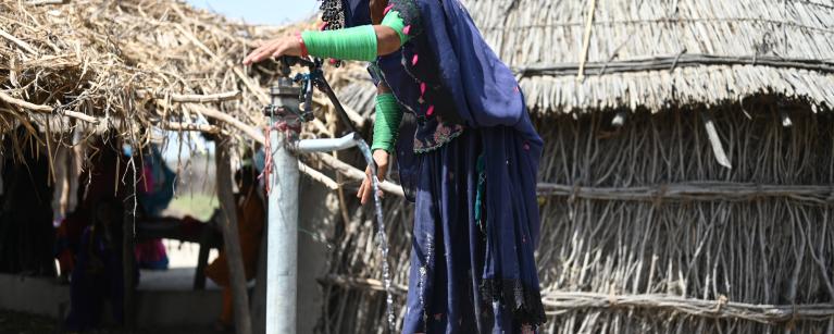 woman from Pakistan using a hand pump