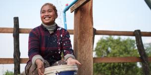 Srey Ngor, Tompuon Indigenous woman smiling as she fetches water from the pipe. Photo: Aimee Han/Oxfam