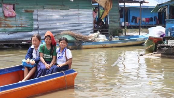 Jing Jing in green t-shirt sitting in the middle on a school boat with her classmate after schooling.