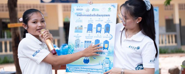Ms. Poern Sreyleak (left), the Varin Water Kiosk Operator, explains the 10-step water treatment process, emphasizing its proven safety and quality standards, as verified by the Pasteur Institute of Cambodia. Photo: Oxfam