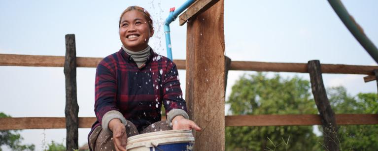 Srey Ngor, Tompuon Indigenous woman smiling as she fetches water from the pipe. Photo: Aimee Han/Oxfam