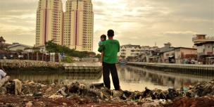 Menatap masa depan: seorang ayah menggendong anak perempuannya ketika berdiri di satu area dimana warga setempat baru saja digusur untuk area pembangunan baru, dekat dengan apartemen mewah di Jakarta Utara, Indonesia. Dalam dua dekade terakhir, ketimpangan antara kelompok orang terkaya dan kelompok lainnya di Indonesia makin meningkat secara lebih cepat ketimbang negara lain di Asia Tenggara. Foto: Tiara Audina/Antropologi UI