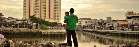 Menatap masa depan: seorang ayah menggendong anak perempuannya ketika berdiri di satu area dimana warga setempat baru saja digusur untuk area pembangunan baru, dekat dengan apartemen mewah di Jakarta Utara, Indonesia. Dalam dua dekade terakhir, ketimpangan antara kelompok orang terkaya dan kelompok lainnya di Indonesia makin meningkat secara lebih cepat ketimbang negara lain di Asia Tenggara. Foto: Tiara Audina/Antropologi UI