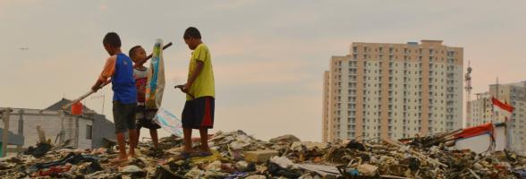 Anak-anak bermain di dekat sungai di satu wilayah dimana warga setempat baru saja digusur untuk pembangunan baru, dekat dengan komplek apartemen mewah di Jakarta Utara, Indonesia. Photo: Tiara Audina/Antropologi UI