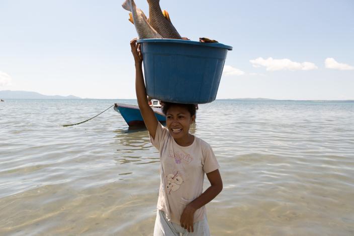 Aisha Selaka, membawa sebakul ikan diatas kepalanya setelah suaminya pulang melaut sejak malam sebelumnya. Aisha dan suaminya tinggal kampung Lewoleba, Nubatukan, Kabupaten Lembata, Provinsi Nusa Tenggara Timur, Indonesia. Credit: Rodrigo Ordonez/Oxfam