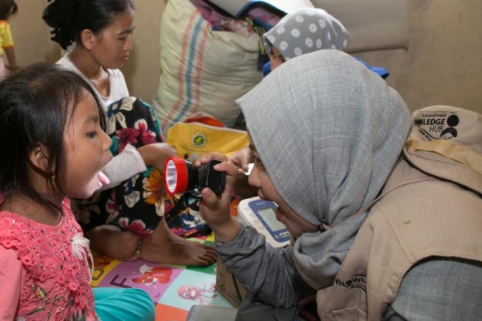 Selat Sunda, Indonesia: Dr. Teza Farida dari PKBI Jakarta mitra Oxfam dalam Jejaring Mitra Kemanusiaan memeriksa tenggorokan dan kesehatan Sophia (kredit: Adrian Mulya/OxfamAUS)
