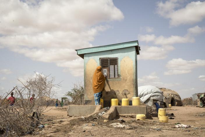 A woman uses her water credit, which is stored in a small, plastic token, to buy water from a Water ATM in Hadado, Kenya.  Credit Katie G. Nelson/Oxfam