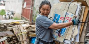 Lao Informal Workers A Lao female informal worker carries a stack of old cardboard boxes for recycling