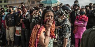 A woman breaks down when a crowd gathers to watch a digger remove rubble from a collapsed building in Gongabu, Kathmandu - Credit: Pablo Tosco/Oxfam