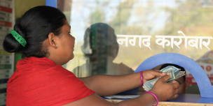 A woman takes out the money send by her husband from India - Credit: Oxfam/OIM/UNDP