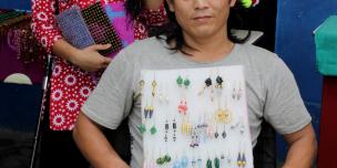 A man displaying beads jewellery he made