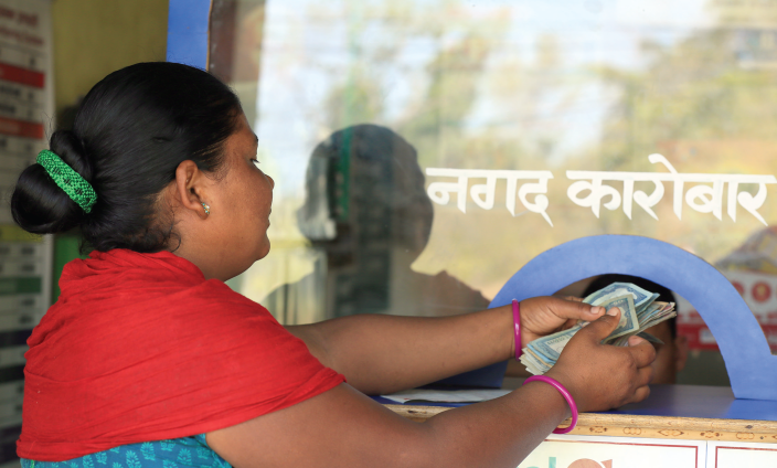 A woman takes out the money send by her husband from India - Credit: Oxfam/OIM/UNDP