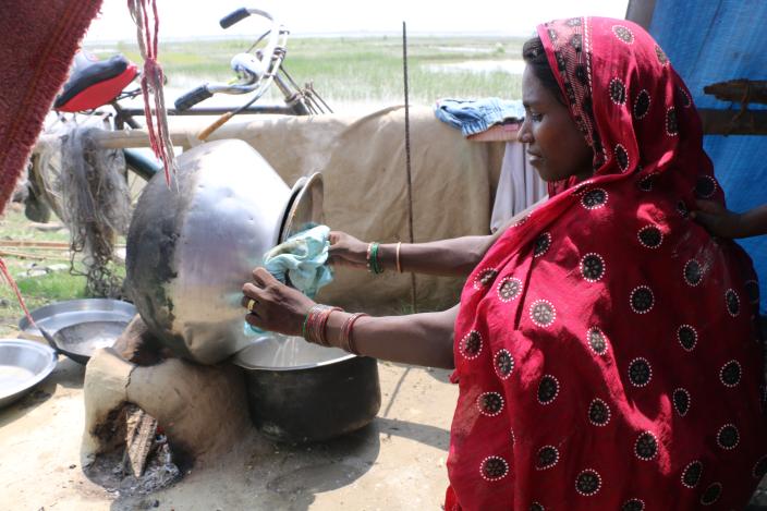 Amirka Sada cooking rice in her makeshift home on an embankment