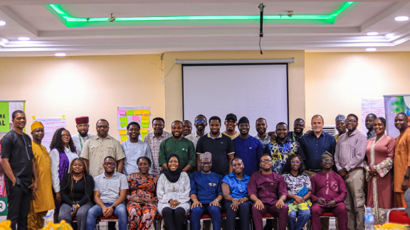 A large group photo of the Oxfam in Nigeria team and partners smiling together in a conference hall after successfully concluding the Country Learning Review.  Photo Credit: Maxwell Osarenkhoe/Oxfam