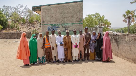 Members of the Peta Ward Development Support Committee standing proudly in front of a rehabilitated public toilet facility.
