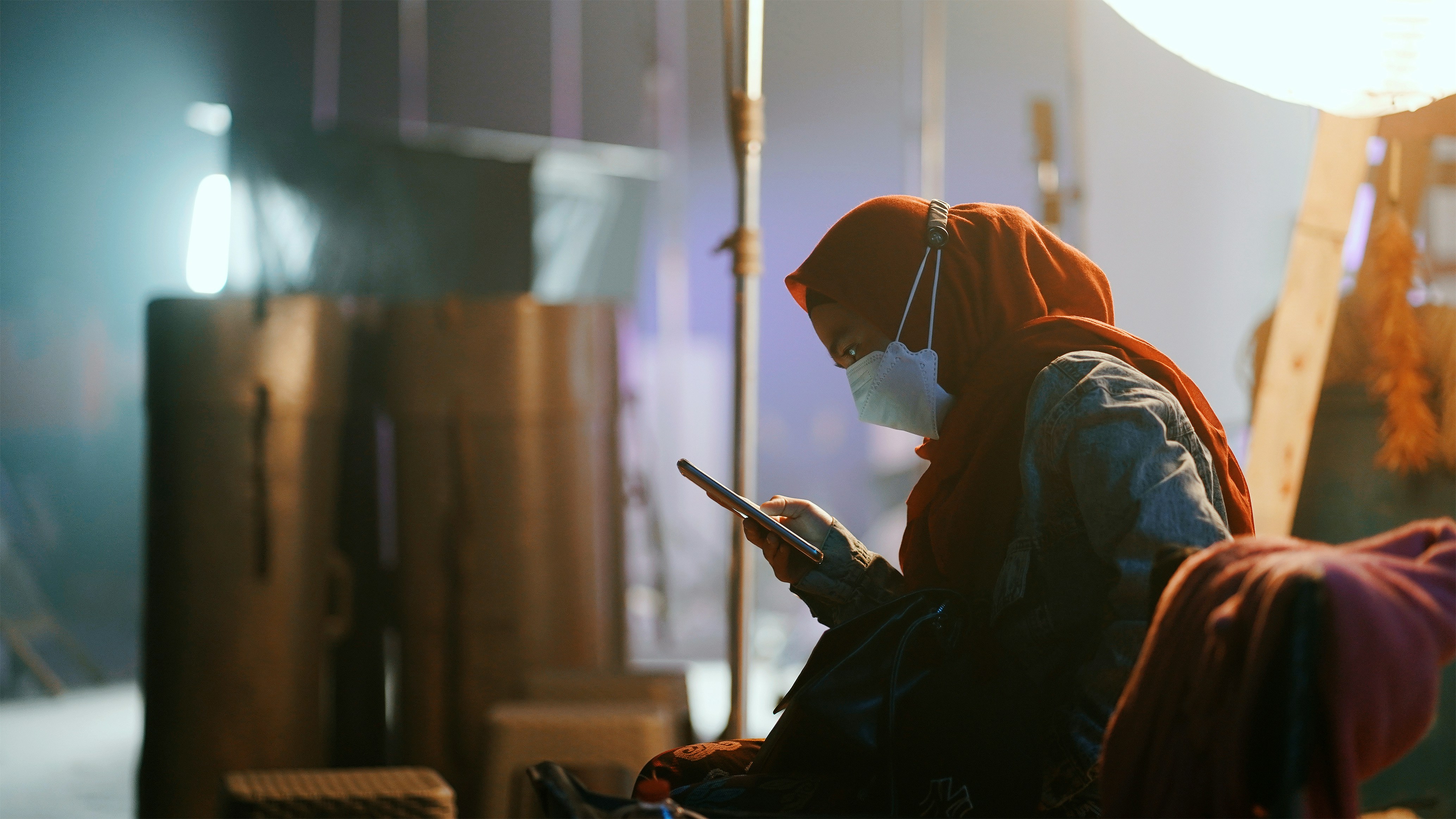 A woman is sitting and looking at her phone.