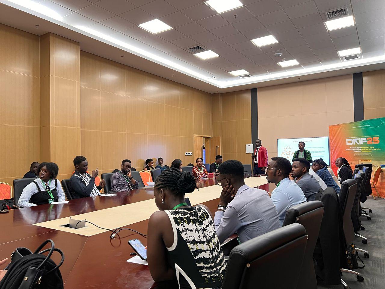 People are gathered, sitting around a table as they listen to a session by ReCIPE partners at DRIF.