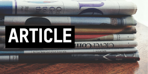 a stack of newspapers sitting on top of a wooden table. Text overlaid reading "article".