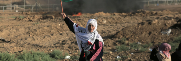 An elderly woman holding a Palestinian flag in Palestine. 