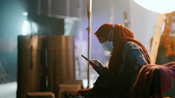 A woman is sitting and looking at her phone.