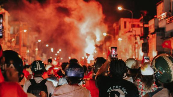 image of a crowd at a protest. A few individuals are recording footage on their phones.