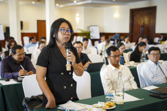 A woman speaks through a microphone to an audience at an event held by the Cooperation Committee for Cambodia (CCC)