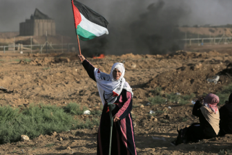 An elderly woman holding a Palestinian flag in Palestine. 