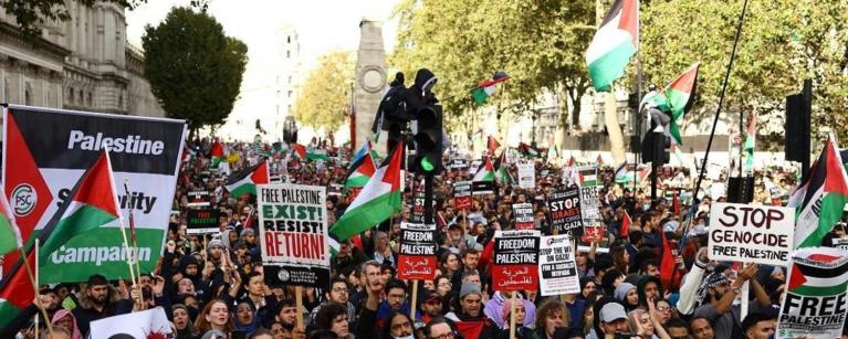 March for Palestine, people waving Palestinian flags and posters.