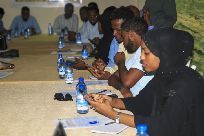 People practice digital skills on their phones at a training held by Somalia Non-State Actors (SONSA).