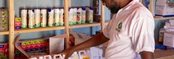 Mustafa, the Oxfam project coordinator, holds a veterinary medication during his visit to the vet shop.