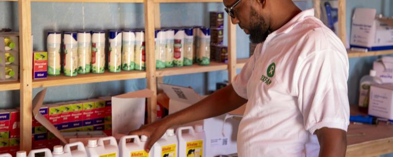 Mustafa, the Oxfam project coordinator, holds a veterinary medication during his visit to the vet shop.