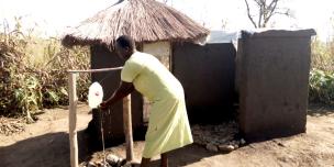 Betty 31 years and single mother of 6 children demonstrates hand-washing at her home latrine Photo: Robert Ariaka/Oxfam