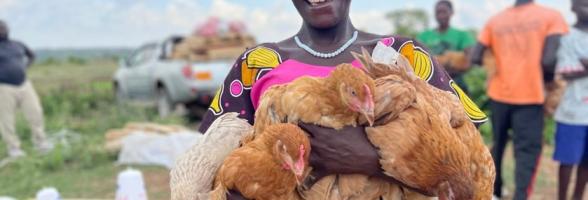 A project participants smiles after receiving her Kuroiler chicken.