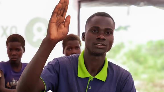 Dengen Moses (22 years) is a learner at Naror mobile learning centre, raises hands to ask questions in class.