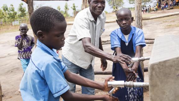 Teacher Simon Said and his pupils using the tapstands constructed by Oxfam Teacher Simon Said and his pupils using the tapstands constructed by Oxfam